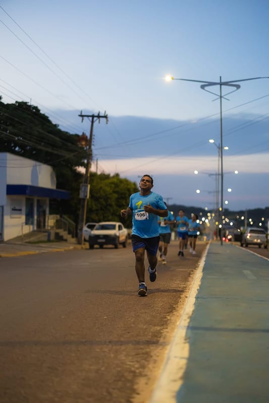 O anoitecer chega e a corrida segue pelas ruas iluminadas.