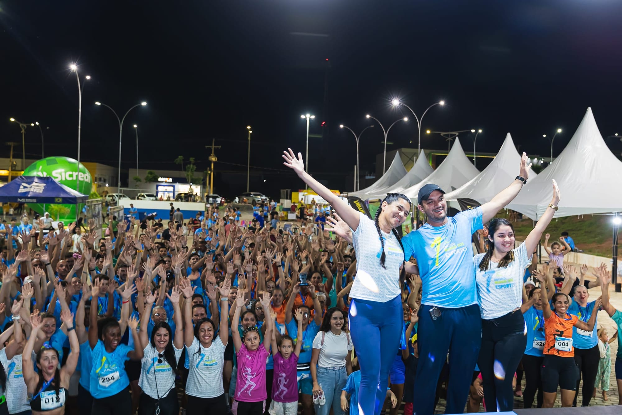 A organização e o público de braços erguidos no encerramento da 1ª edição, à noite, com as tendas ao fundo